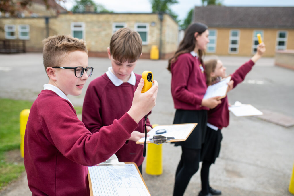 A group of pupils outdoors holding clipboards and measuring devices.