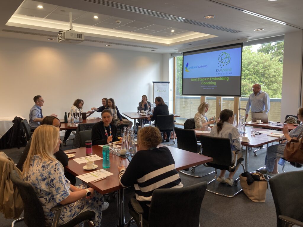 A large group of people in conference setting split up into smaller groups for discussions.