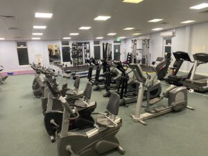 An indoor gym with gym equipment including a cycling machine and running machines.