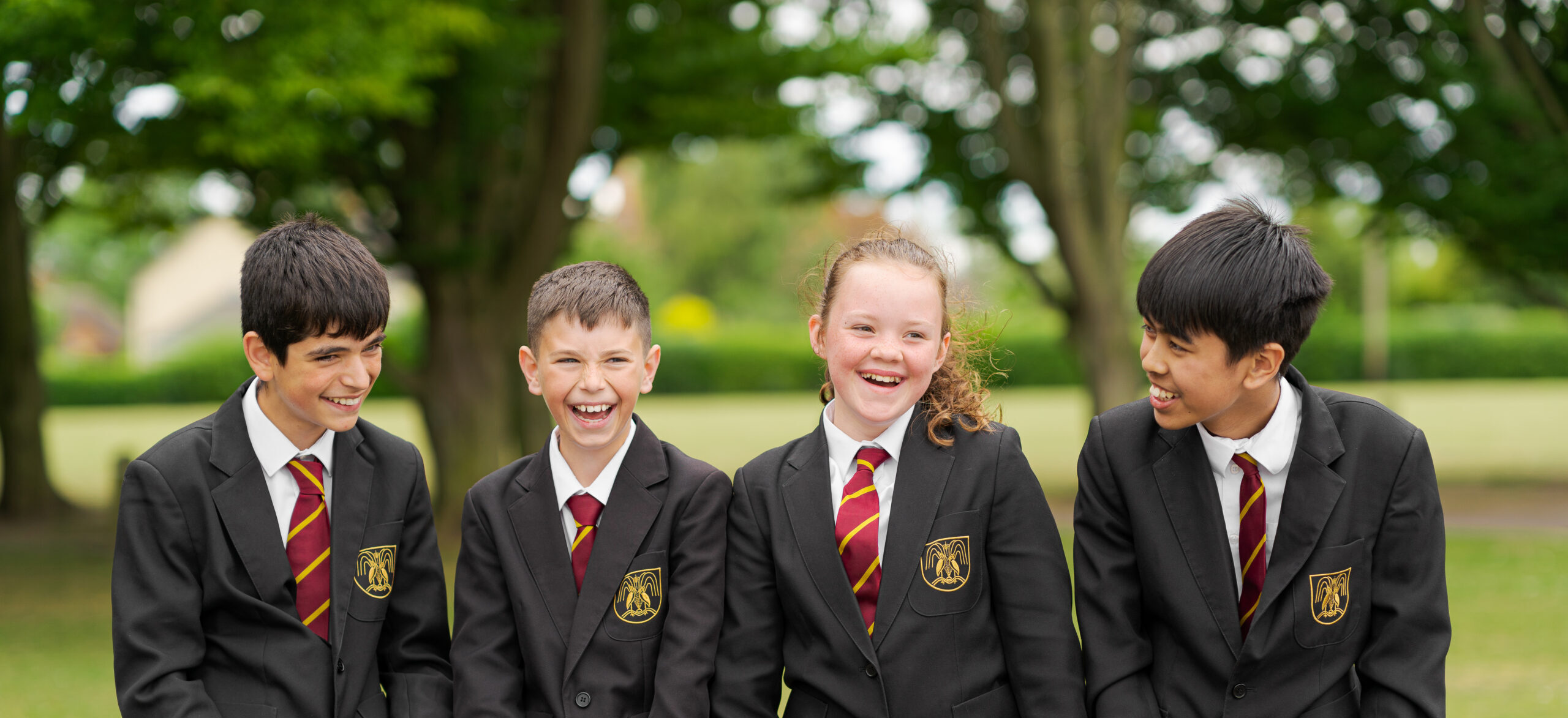 A group of students smiling at each other outdoors.