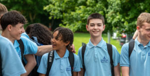 A group of students smiling at each other in an outdoor setting.