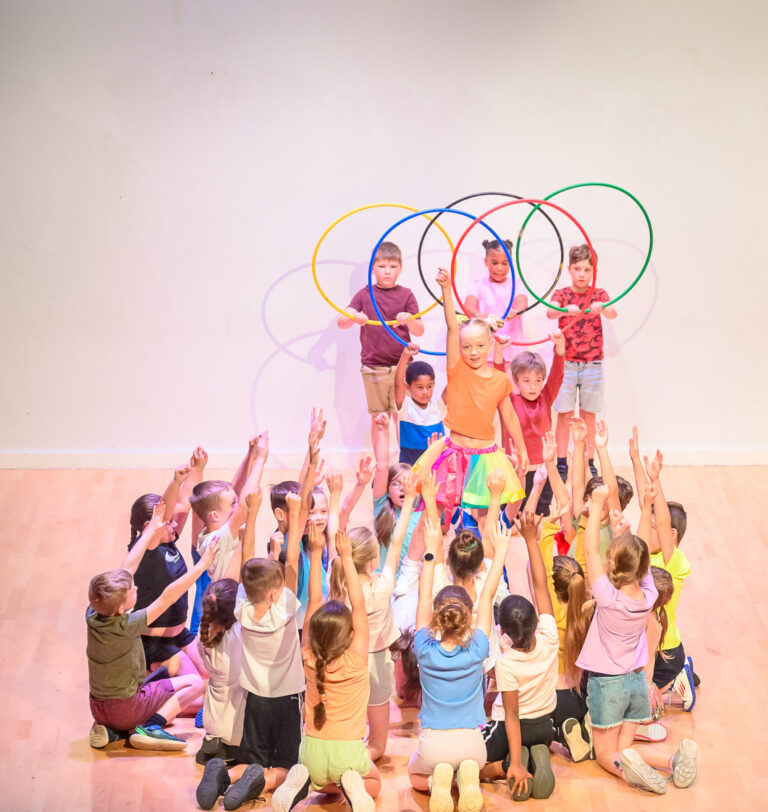 A group of children performing on stage holding hula hoops.